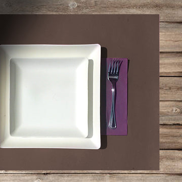 Apparecchiatura con tovaglietta americana marrone, tovagliolo di carta viola e due piatti in polpa di cellulosa quadrati uno sopra l'altro